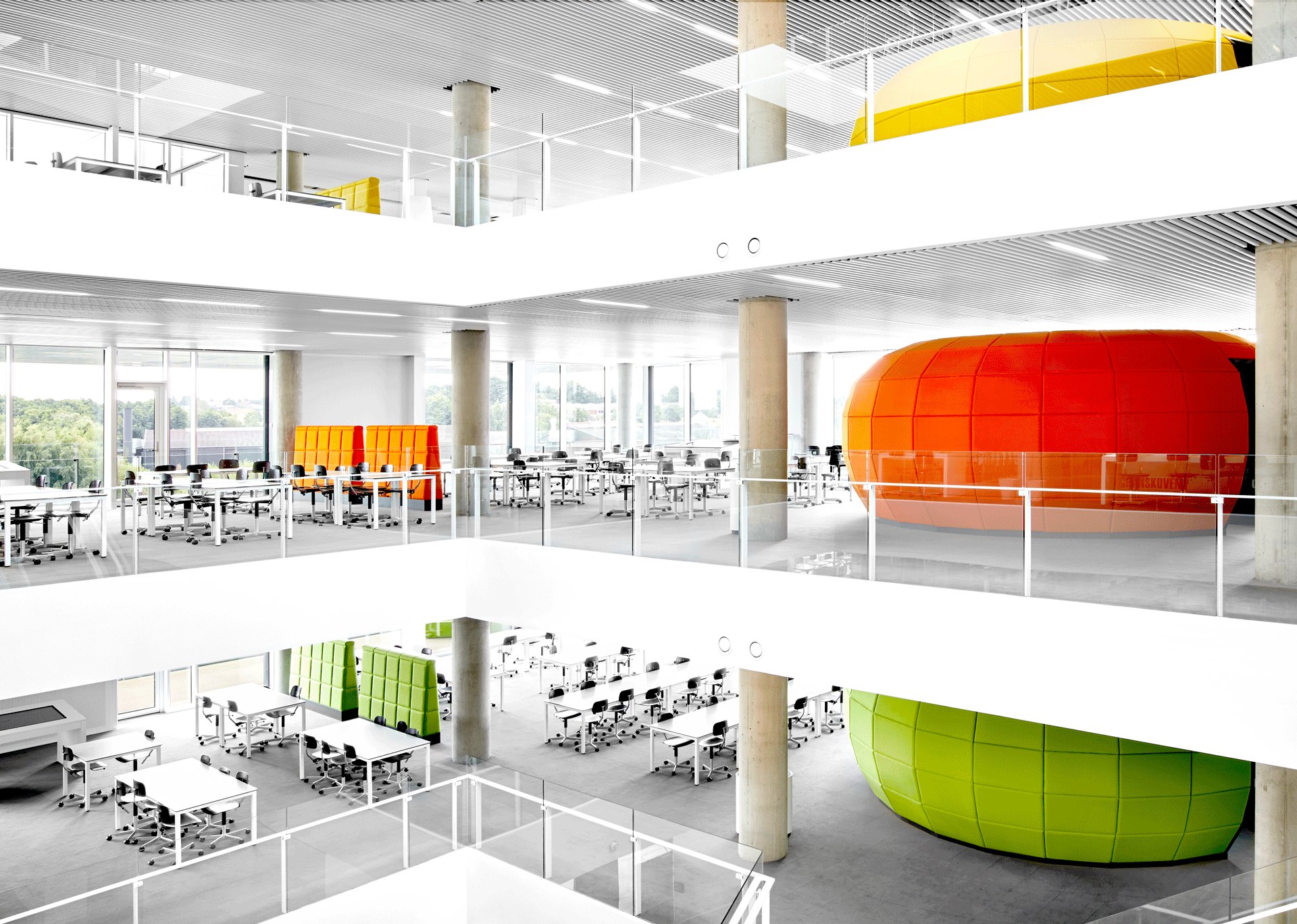Lyst atrium over flere etager med orange, gule og grønne mødekapsler